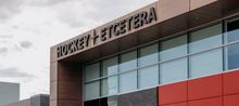 Top left of a building covered in glass windows and surrounded by a wood border with black letters that read 'Hockey Etcetera'
