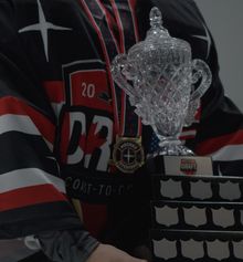 A close up photo of a goalie holding the trophy at the Hockey Etcetera Coast to Coast showdown in 2023